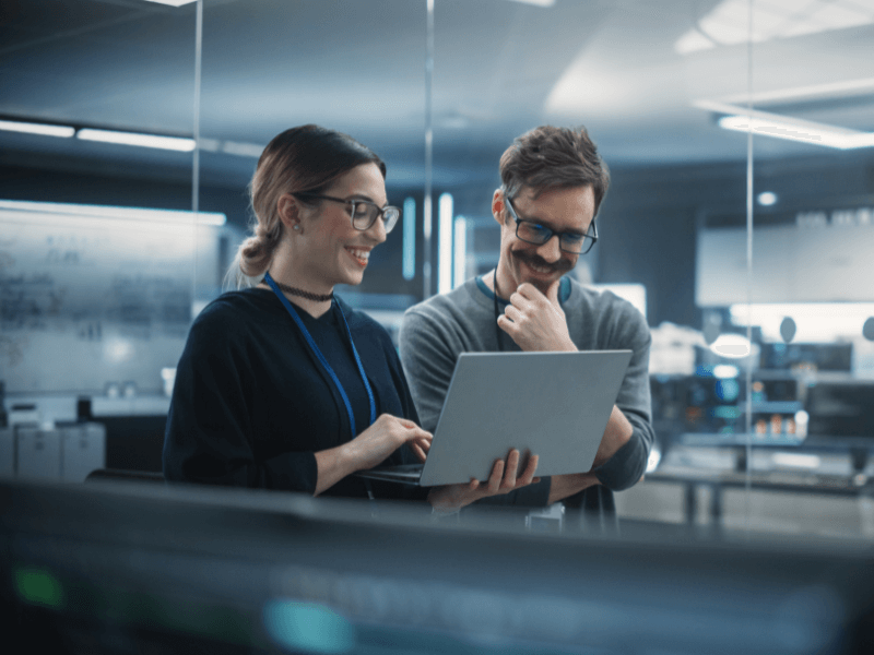 Two people collaborating while looking at a laptop in a modern office