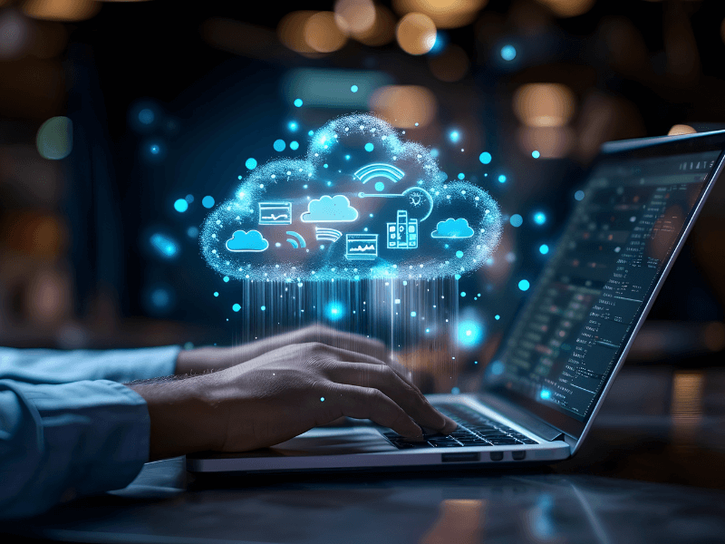 A laptop with hands typing and a glowing cloud illustration above it, symbolizing cloud computing.
