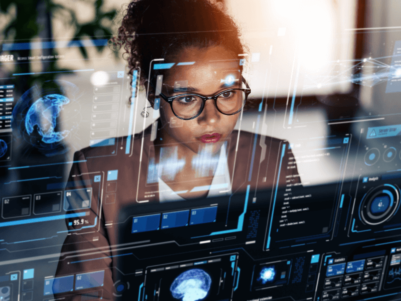 Person in glasses using a futuristic transparent screen with digital interfaces.