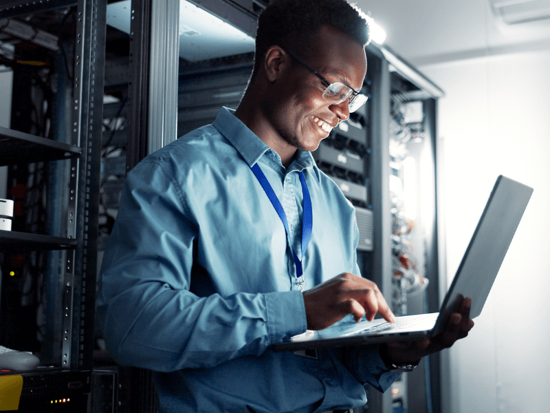 A person in a server room working on a laptop.