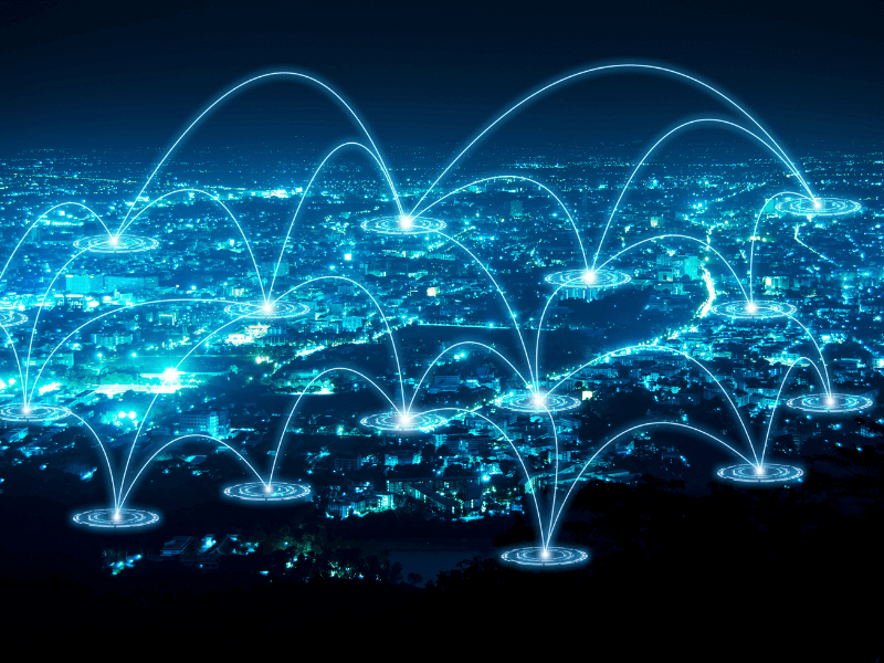 A night cityscape with glowing arcs and nodes symbolizing a digital network.